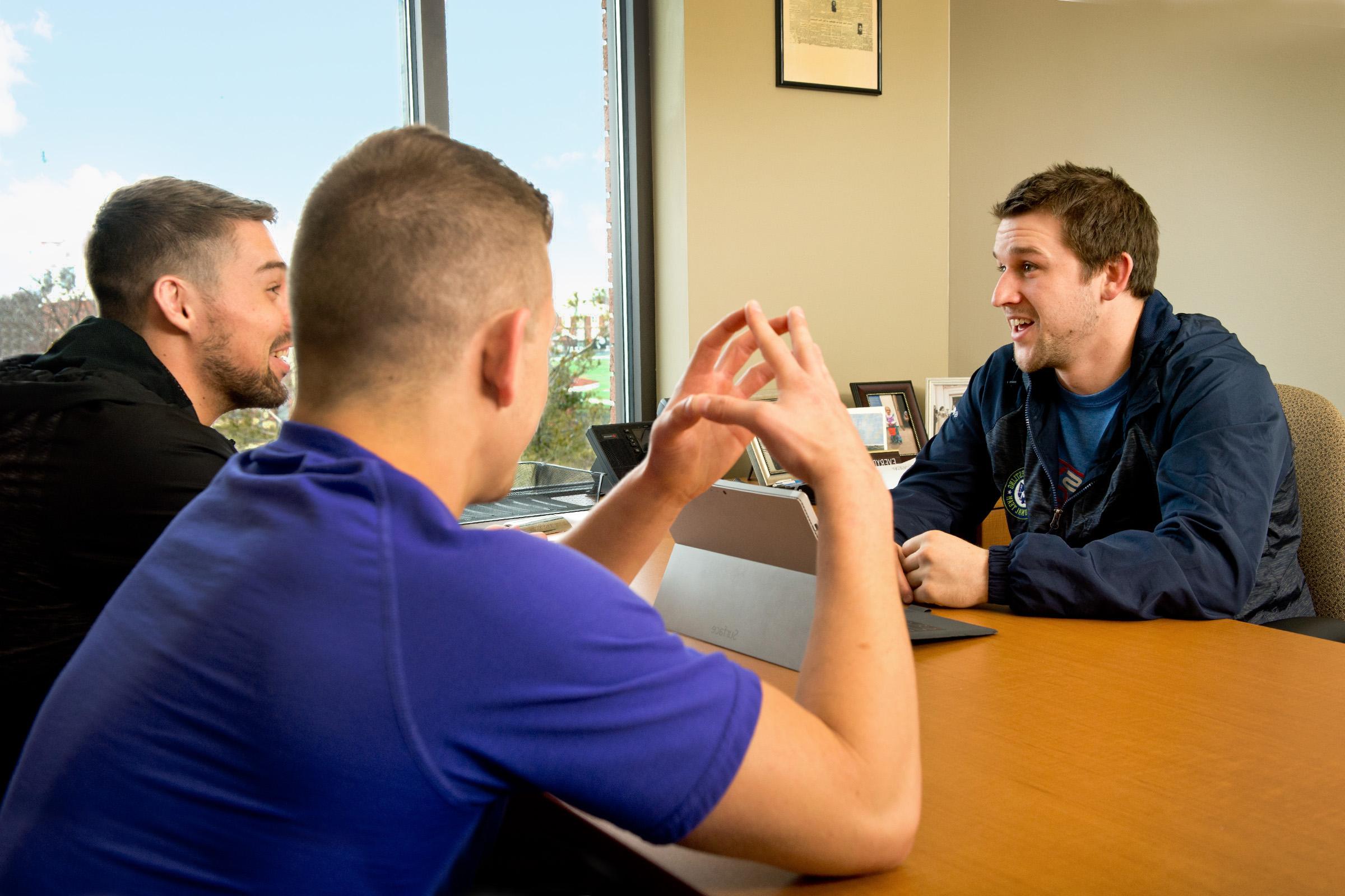 Wrestling coach meeting with athletes in his office.